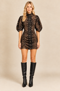 Blonde model wearing the printed mini dress with black leather knee-high boots