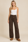 Brown jeans styled on a blonde model in a neutral studio