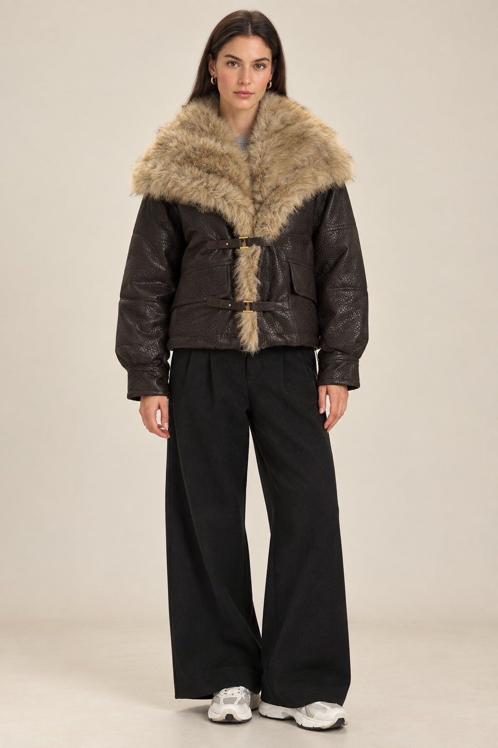Brunette model in a plain studio wearing the textured brown PU coat