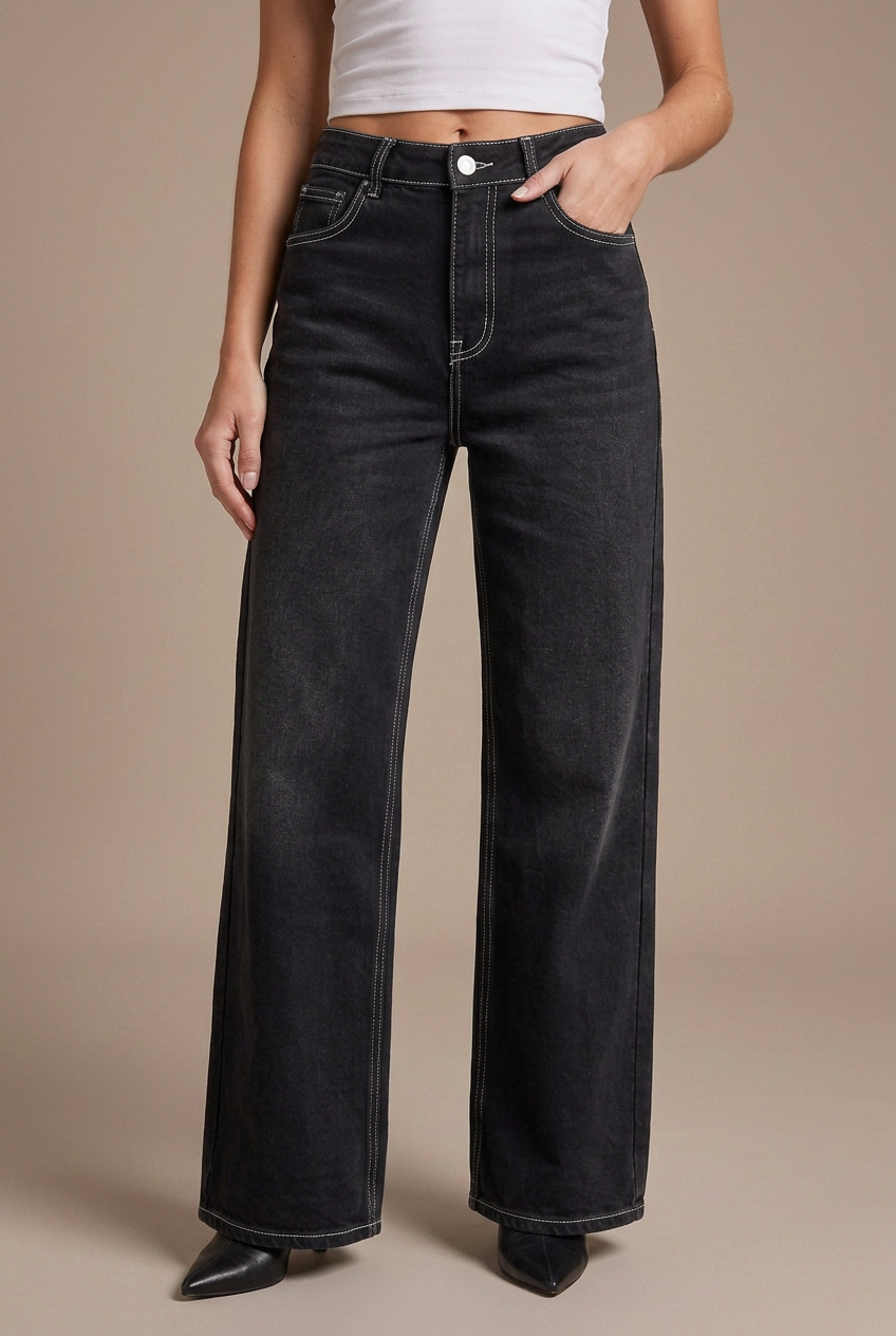 Close-up studio shot of black contrast-stitch wide-leg jeans on the model