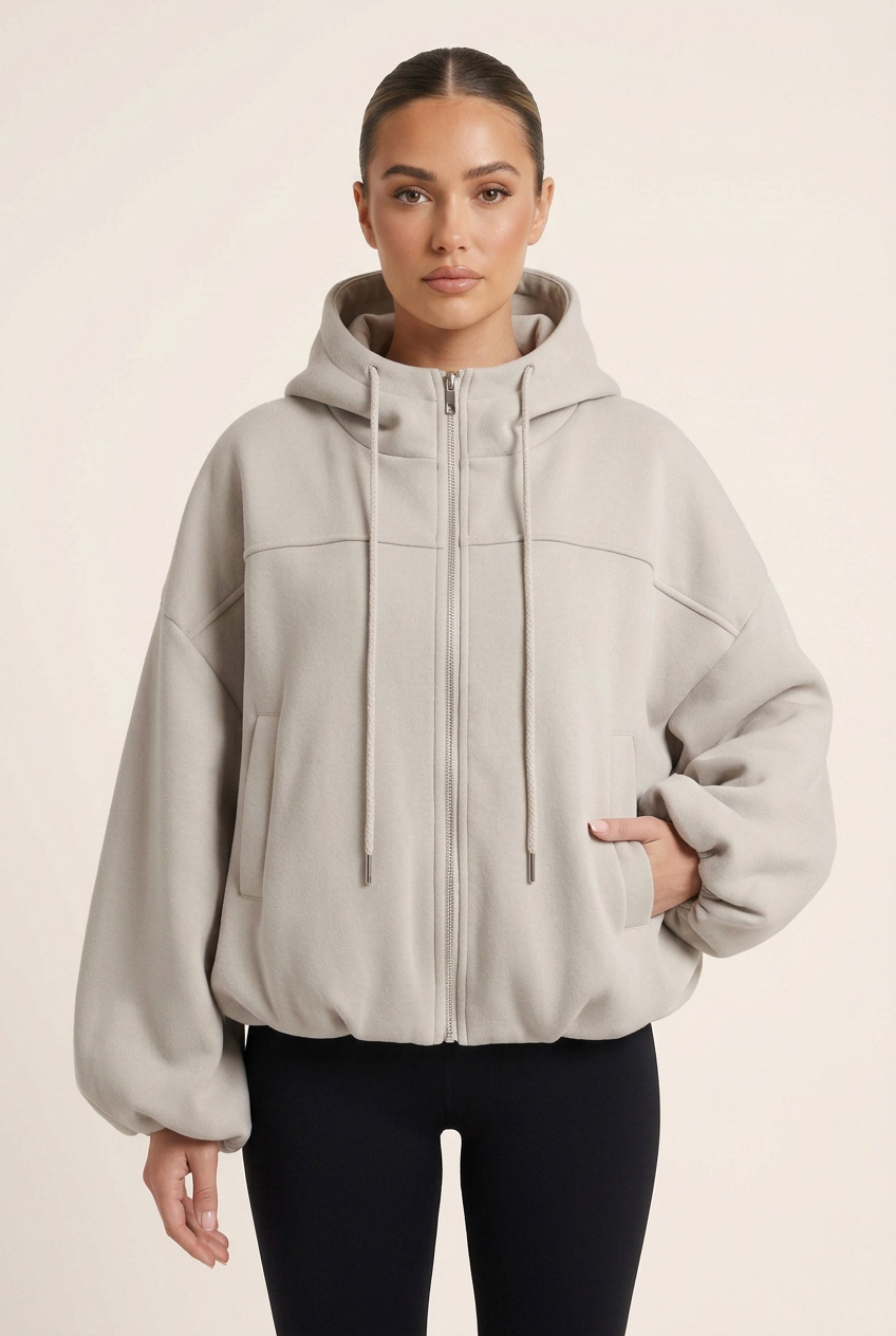 Front-facing close-up of the jersey jacket with a new hand-in-pocket pose and sleek brunette bun
