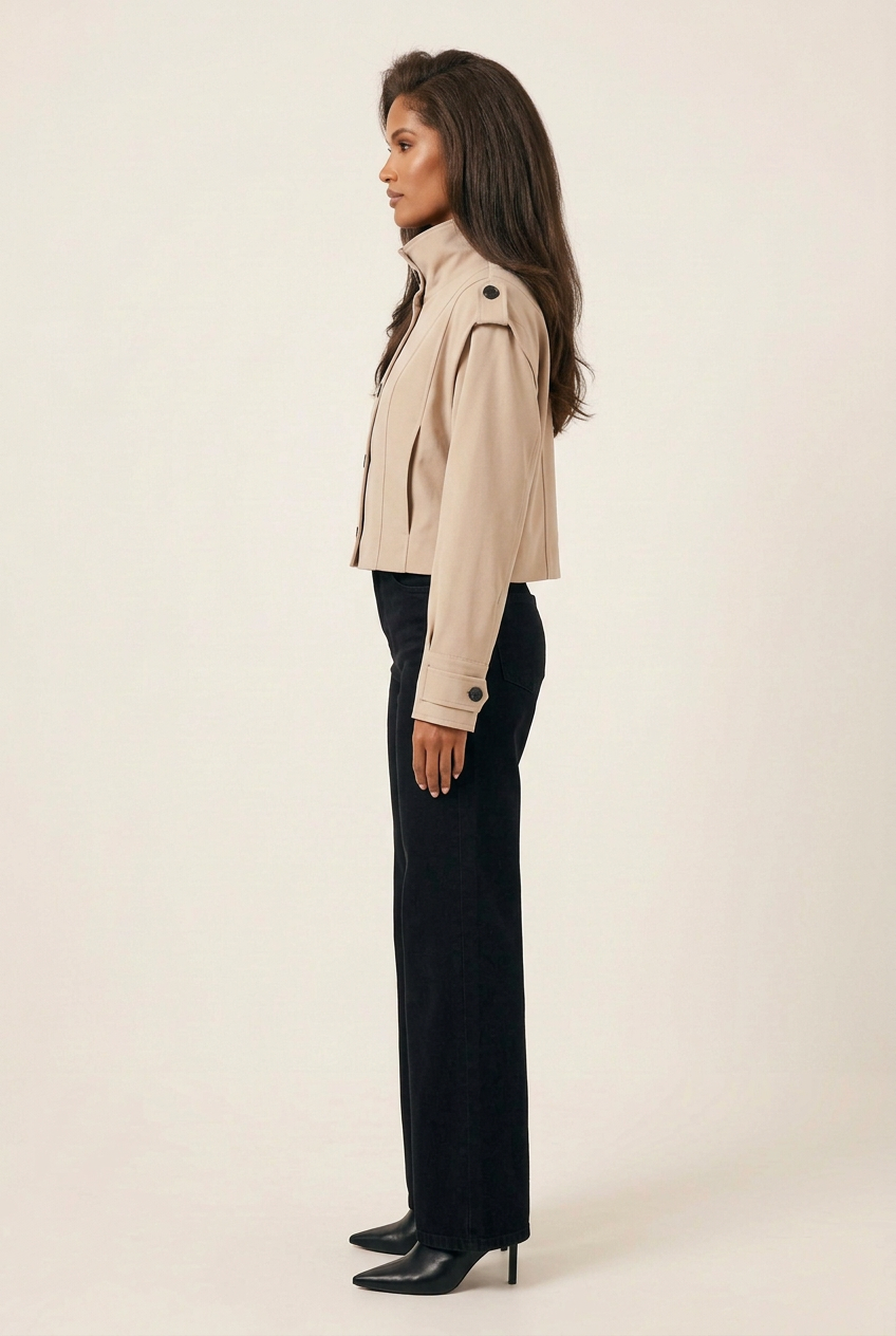 Full-length side profile of the brunette model wearing the beige jacket, black wide-leg jeans and pointed-toe heeled boots