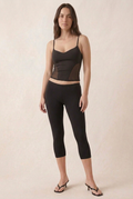 Full outfit with a small midriff gap between the black cami and low-rise capri leggings