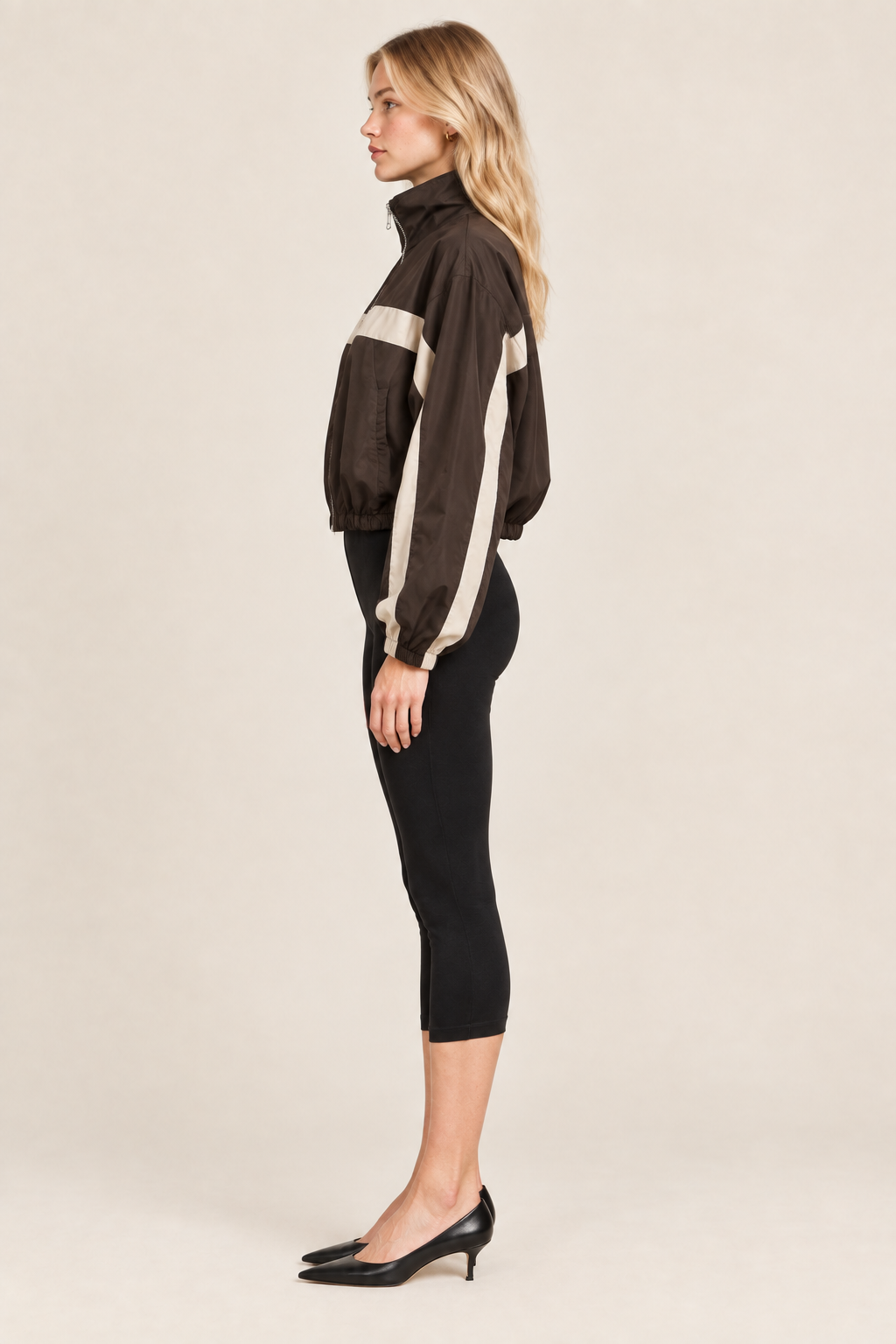 Side profile of blonde model in brown striped track jacket