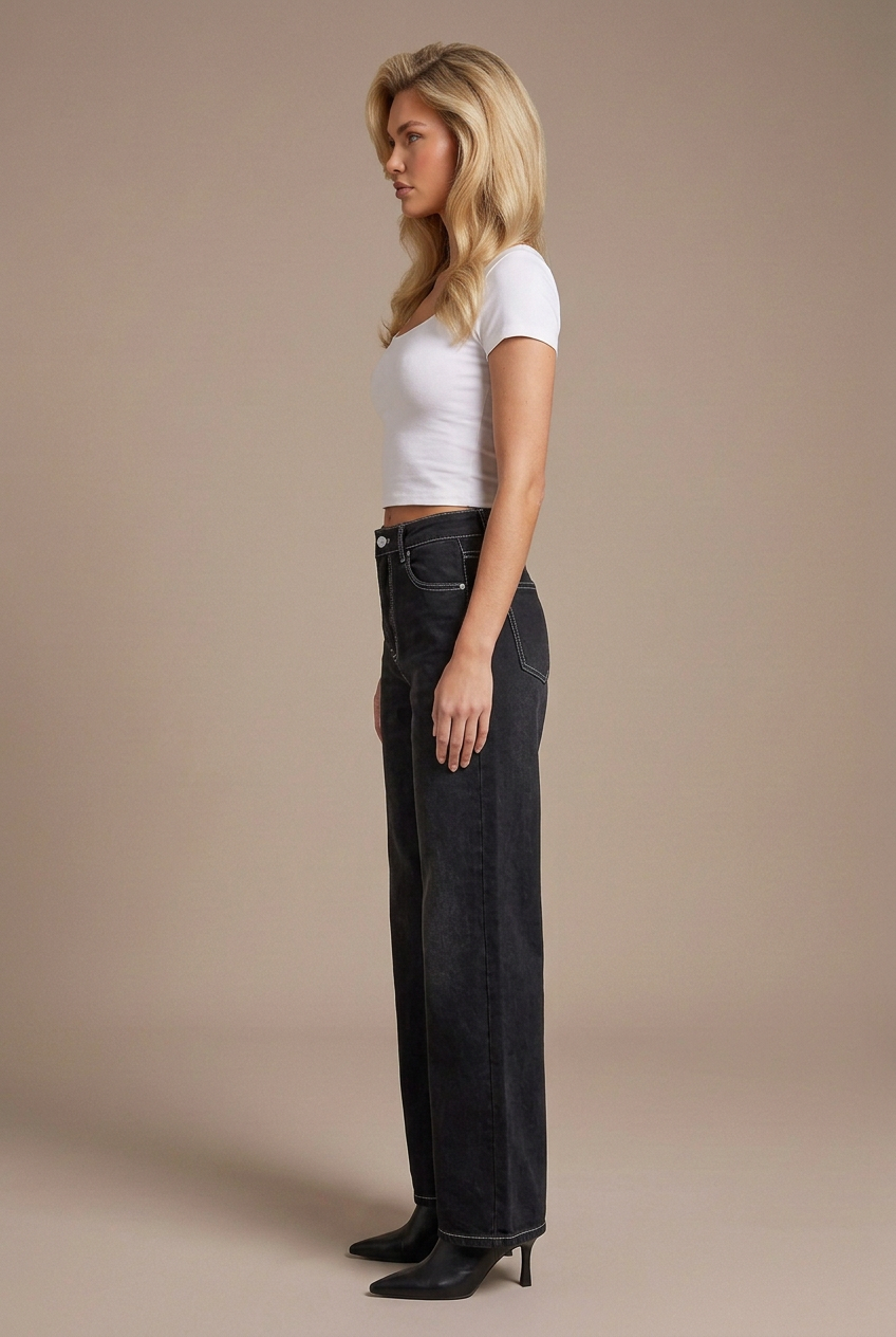 Side profile studio image of blonde model in black contrast-stitch wide-leg jeans, white tee, and black leather boots