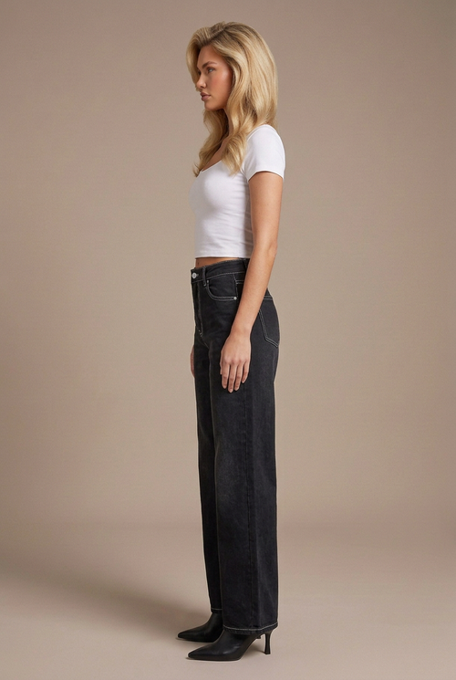 Side profile studio image of blonde model in black contrast-stitch wide-leg jeans, white tee, and black leather boots