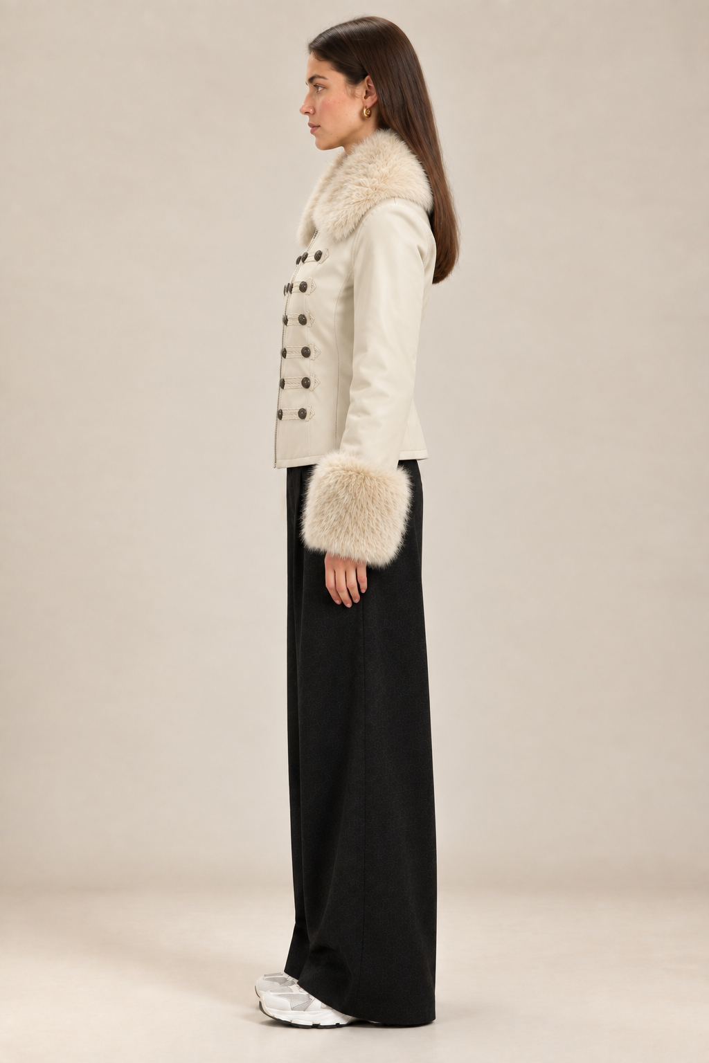 Side-profile studio image of the brunette model wearing the cream military-style jacket