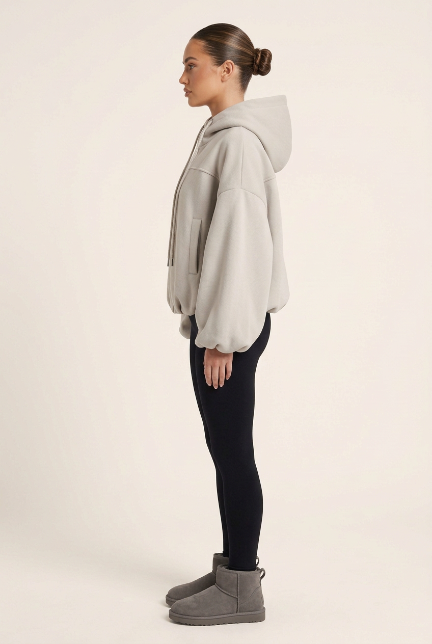 Side-profile studio image of the jersey jacket with black leggings, grey Ugg-style boots and a sleek brunette bun